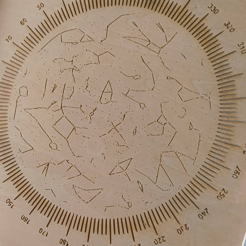 Framed star map with engraved design on a wooden surface